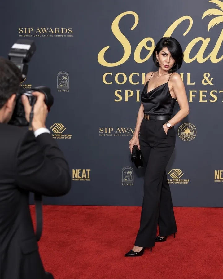 A guest posing on the red carpet for a photographer in front of the SoCal Cocktail & Spirits Fest backdrop