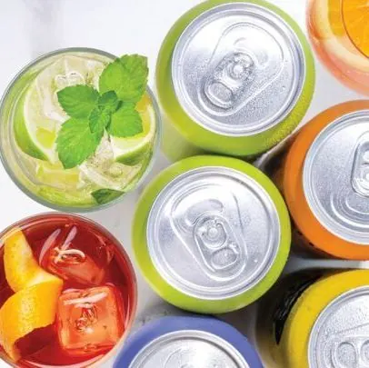 Colorful canned drinks next to a cocktail garnished with mint and lime